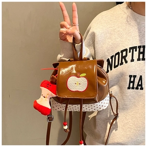 Close-up of brown glossy mini backpack with apple embroidery and polka dot detail
