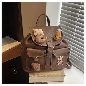 Detail of dark brown leather kid's backpack with vintage buckles and cute cartoon charms