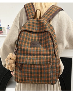 Detail of checkered mini backpack with plush bear charm and brown leather logo tag