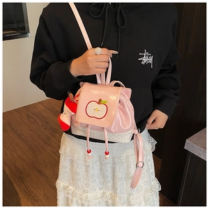 Close-up of pink glossy patent leather kids backpack with apple embroidery and polka dots
