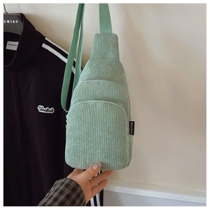 Details einer hellgrünen Cord-Brusttasche mit drei Reißverschlüssen und verstellbarem Gurt