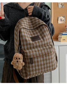 Detail of plaid backpack featuring a brown poodle plush charm and vintage tweed fabric