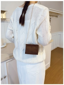 Detailansicht braune matte Kindertasche mit Goldkette auf weißem Strickpullover