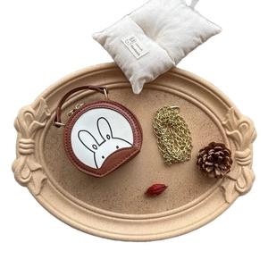 Mini round cartoon rabbit shoulder bag with gold chain strap in a rustic decorative tray