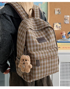 Detail of vintage plaid kids backpack with leather label and plush puppy pendant accessory