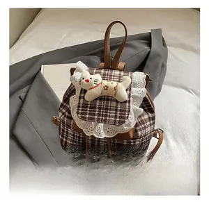 Detail of checkered girl's backpack featuring white lace trim and a cute plush cat doll