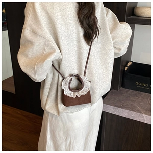 Detail of vintage brown suede mini crossbody bag with white lace trim and slim strap