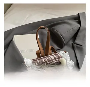 Detail of checkered schoolbag featuring white lace trim and a plush puppy pendant