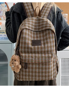 Detail of plaid kids backpack with vintage pattern and cute plush puppy charm
