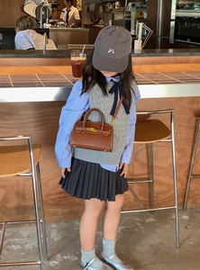Detailed view of a brown leather mini crossbody bag styled with a child fashion outfit
