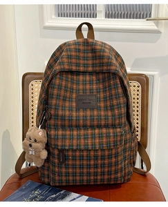 Close-up of vintage plaid children backpack with a cute brown plush bear charm