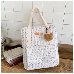 Close-up of quilted floral backpack with Merci embroidery and brown plush bear charm