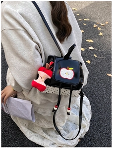 Close-up of cute cartoon apple backpack with polka dot patterns and plush apple charm