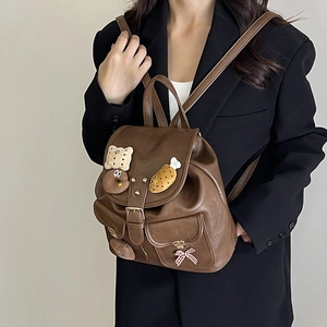 Kids leopard print leather backpack with cute plush charms and bow, worn by model