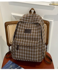 Detailed close-up of a vintage plaid kids backpack with leather logo on a stylish chair