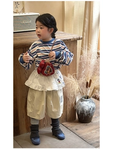 Détail du sac à bandoulière rouge en forme de cœur avec chaîne sur tenue rayée enfant