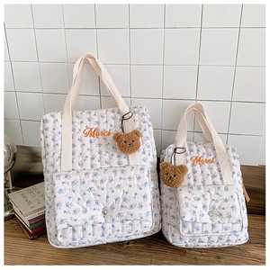 Detail of floral quilted cotton backpacks with Merci embroidery and brown plush bear charms