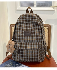 Detail of plaid backpack featuring British style tweed fabric and brown leather logo patch