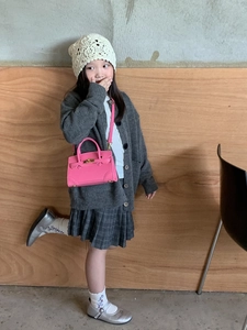 Close-up of a mini rose pink PU leather tote bag with gold buckle on a child model