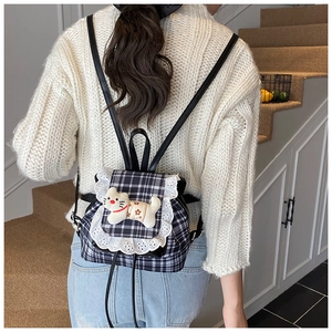 Close-up of girls plaid backpack featuring white lace trim and a cute plush kitten doll