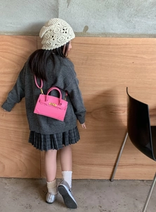 Pink mini structured tote bag for kids with gold hardware shown on a child model