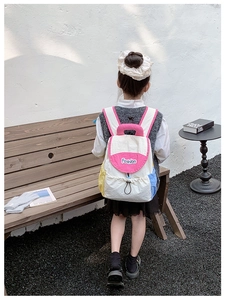 Toddler wearing a lightweight color-block backpack with drawstring on wooden bench