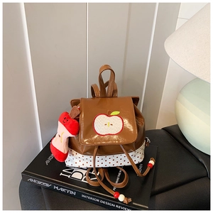 Detail of a brown glossy mini backpack with apple embroidery and polka dot patterns