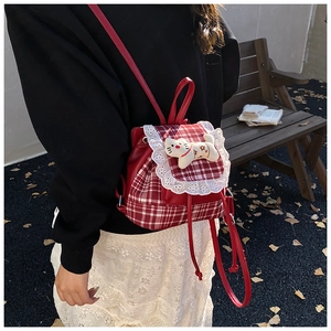 Detail of red plaid toddler backpack with lace trim and plush kitten pendant charm