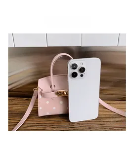 Pink polka dot mini crossbody bag shown next to a smartphone to demonstrate small size