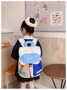 Detail view of stylish color-block kids backpack with drawstring side pockets and buckles