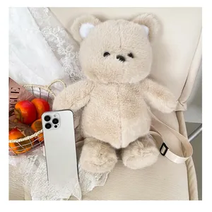 Detailed scale view of plush bear backpack next to a smartphone for size reference