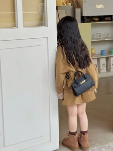 Close-up of black lychee grain mini leather handbag with golden lock on a child model