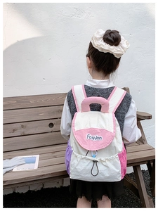 Outdoor back view of a lightweight color-block kids backpack with Fashion text logo