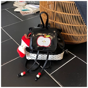 Detailed view of kids' backpack featuring apple embroidery and polka dot patterns