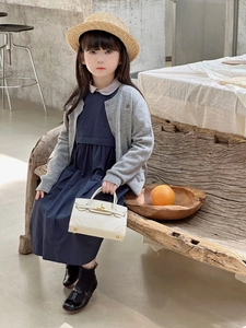 Kids' white mini handbag with metal clasp paired with a gray knit cardigan outfit