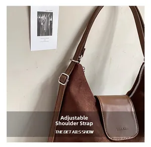 Détail de la boucle argentée sur la bandoulière réglable d'un sac en daim marron