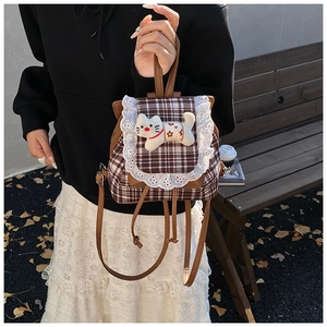 Detailed view of checkered toddler backpack featuring white lace trim and a plush cat doll