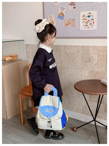 Toddler wearing a color-block lightweight backpack in a cozy cafe lifestyle setting