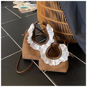 Close-up of caramel brown suede kids bags featuring vintage white lace ruffle trim handles