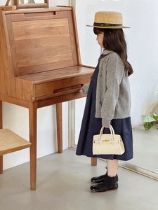 Mini cream flap handbag styled with a grey cardigan and blue dress for a classic look