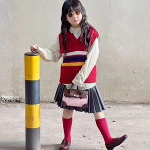 Minimalistische Kinder-Umhängetasche in Farbkombination mit roter Strickweste und Rock