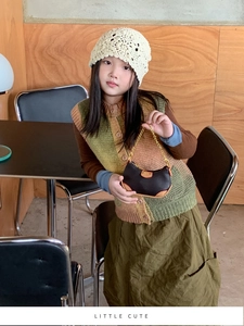 Toddler girl holding a black mini crescent bag with gold chain and autumn knitwear