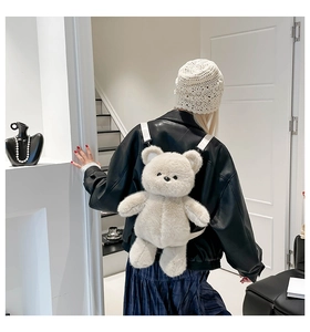 Detail view of a cute cream plush bear backpack on a child with soft faux fur texture