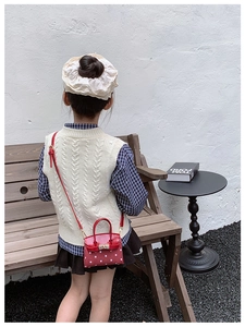 Detail of red polka dot kids mini bag with metal clasp and cross-body strap
