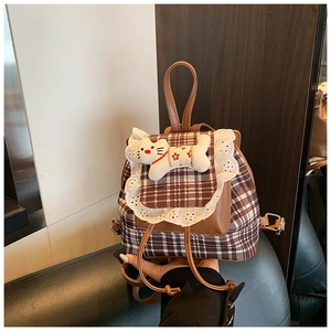 Detailed view of plaid kids backpack with lace trim and cute plush cat doll ornament