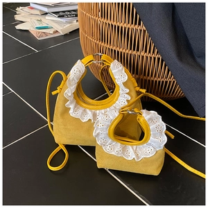 Detail of yellow suede mini bag with white lace handle decoration and crossbody strap