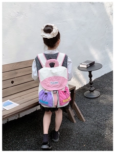 Rear view of a child wearing a stylish tricolor color-block backpack with drawstring pockets