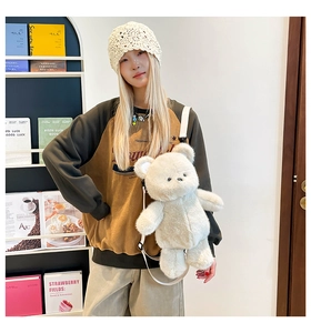 Detail of white plush bear backpack with adjustable strap on a child model