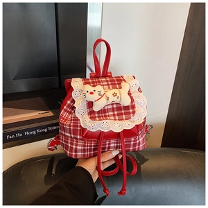 Detail of red checkered backpack with white lace trim and cute plush cat doll