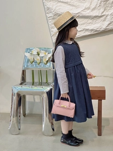 Detail view of a navy quilted vest dress paired with a grey plaid shirt for girls